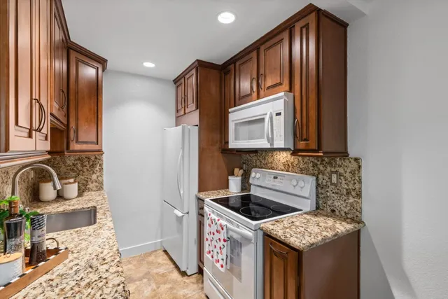 a kitchen with stainless steel appliances granite countertop a stove a sink and a microwave