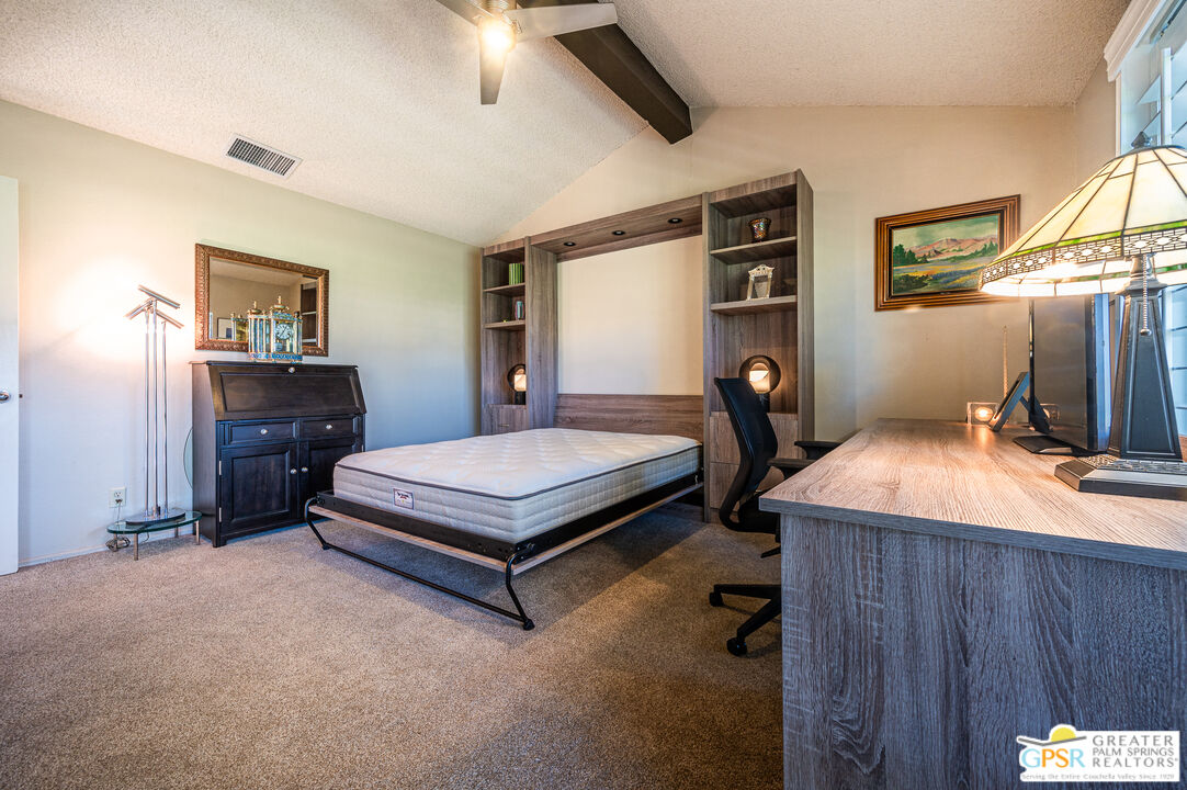 6000 East Driver Road Palm Springs, CA 92264 - Photo 28 of 40 a bedroom with a bed and a chandelier