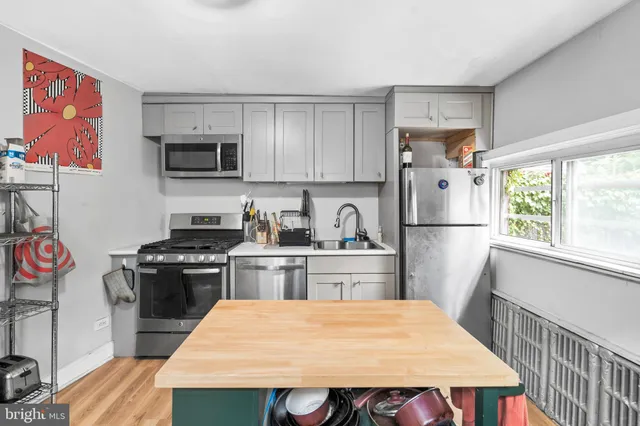 a kitchen with stainless steel appliances a stove a sink dishwasher a refrigerator white cabinets and wooden floor