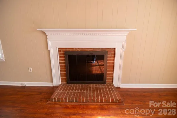a view of an empty room with wooden floor and a fireplace