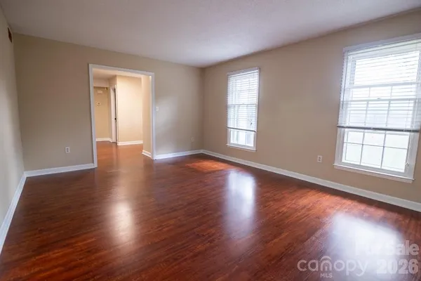 an empty room with wooden floor and windows with curtains view