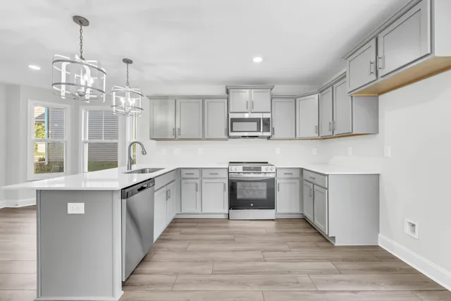 a kitchen with stainless steel appliances granite countertop a refrigerator a stove top oven a sink dishwasher and white cabinets with wooden floor
