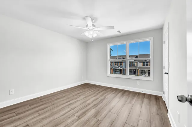 a view of an empty room with wooden floor and a window