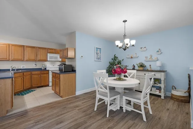 a dining room filled a chandelier and kitchen view
