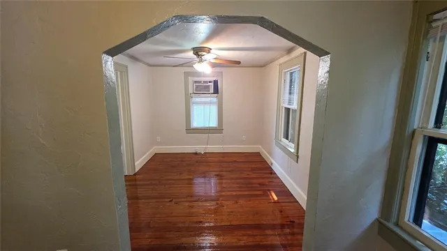 a view of an empty room with wooden floor and a window