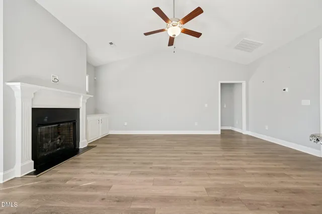 a view of empty room with wooden floor and fireplace