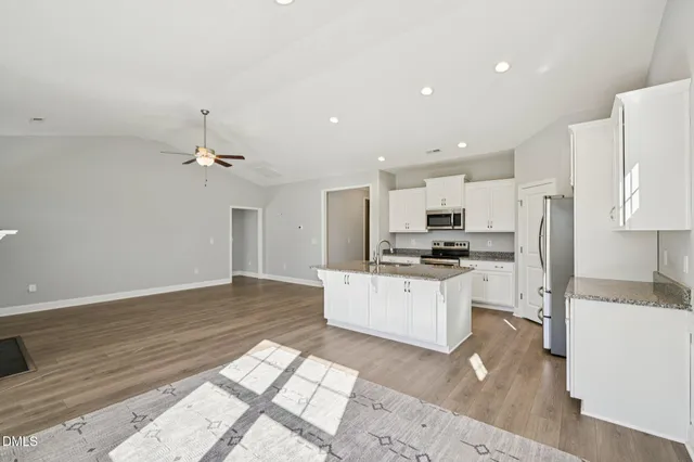 a kitchen with stainless steel appliances kitchen island granite countertop a refrigerator and a sink