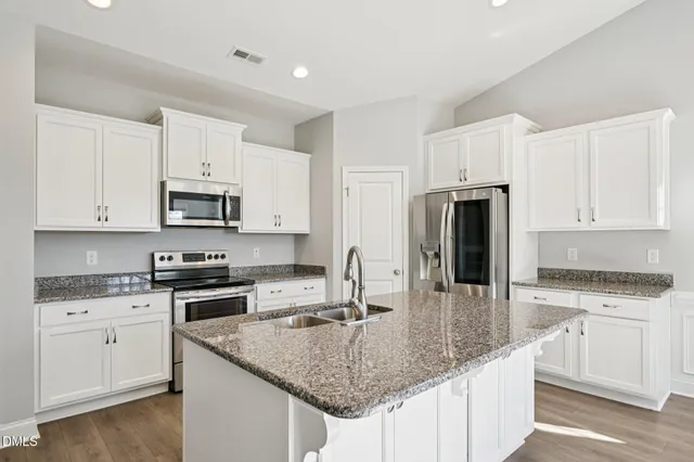 a kitchen with stainless steel appliances granite countertop a sink stove and refrigerator
