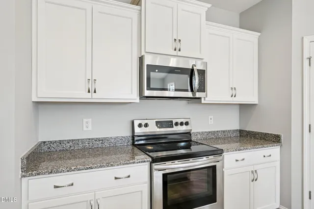 a kitchen with granite countertop white cabinets stainless steel appliances and wooden floor