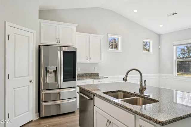 a kitchen with stainless steel appliances granite countertop a refrigerator and a sink
