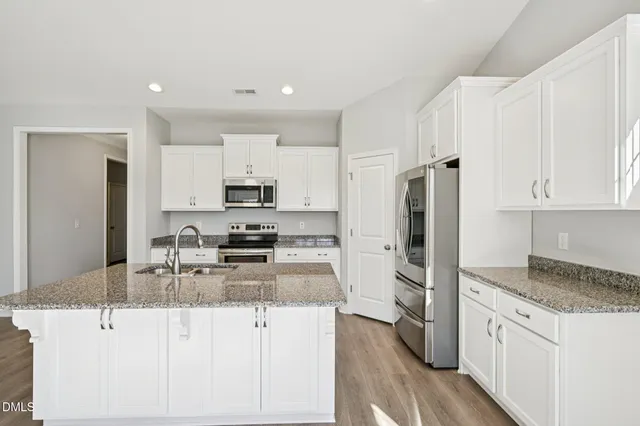 a kitchen with stainless steel appliances granite countertop a refrigerator and a stove top oven