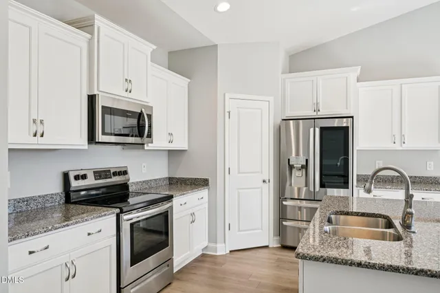 a kitchen with granite countertop white cabinets and stainless steel appliances