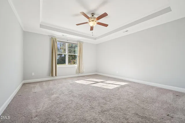 an empty room with ceiling fan and windows