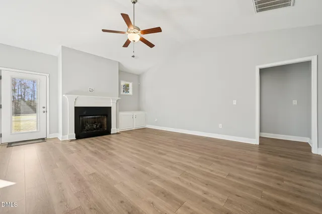 an empty room with ceiling fan and fireplace