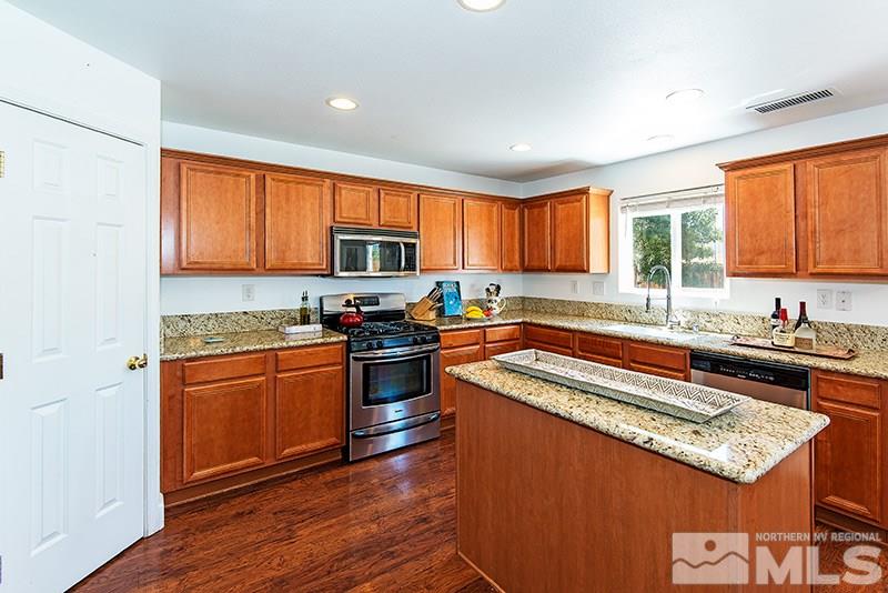 2916 Bryan Street Reno, NV 89503 - Photo 9 of 18 a kitchen with granite countertop a stove top oven a sink dishwasher a dining table and chairs with wooden floor