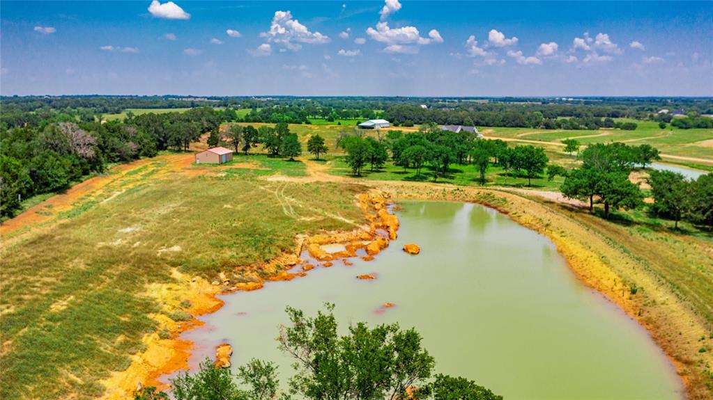 1789 Brumelow Road Whitesboro, TX 76273 - Photo 15 of 30 Expansive acreage featuring a substantial pond, mature trees, open fields, and a barn structure