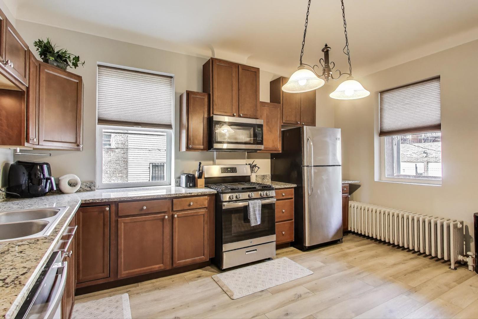 2720 West Polk Street, Unit 1 Chicago, IL 60612 - Photo 7 of 13 a kitchen with stainless steel appliances granite countertop a sink a stove a refrigerator cabinets wooden floor and a window