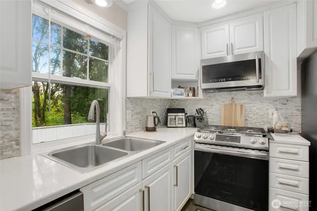 a kitchen with stainless steel appliances a stove microwave and sink