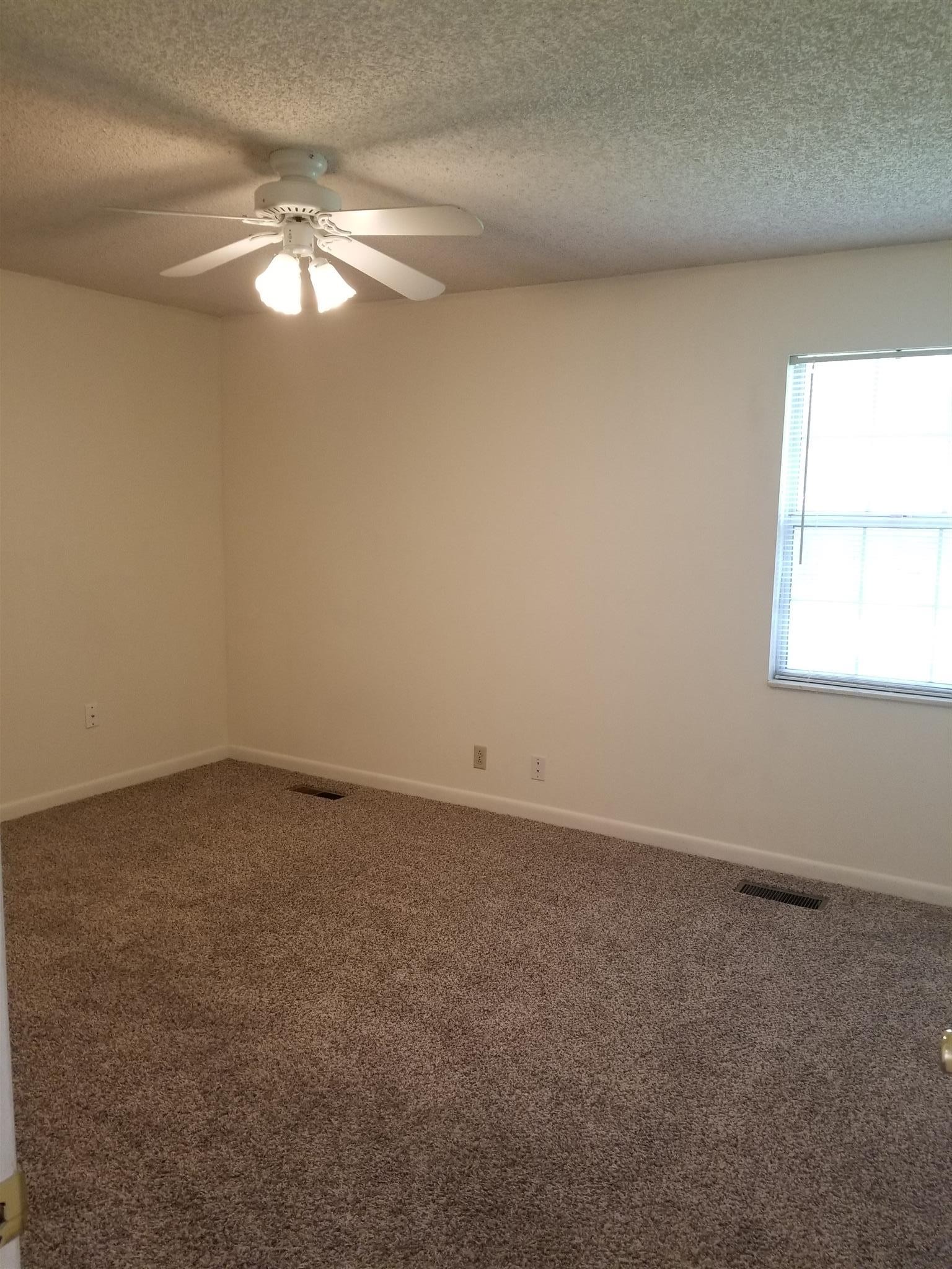 3116 Stoneybrook Circle Antioch, TN 37013 - Photo 10 of 13 an empty room with a chandelier fan and windows