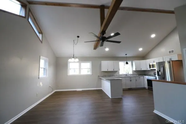 a kitchen with stainless steel appliances kitchen island hardwood floor sink stove and wooden cabinets