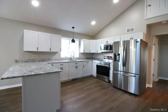 a kitchen with granite countertop stainless steel appliances a refrigerator sink and microwave