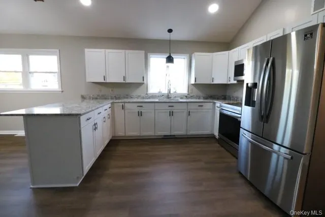 a kitchen with granite countertop stainless steel appliances a sink cabinets and a window