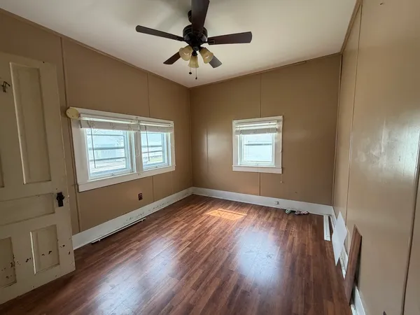a view of an empty room with a window and wooden floor