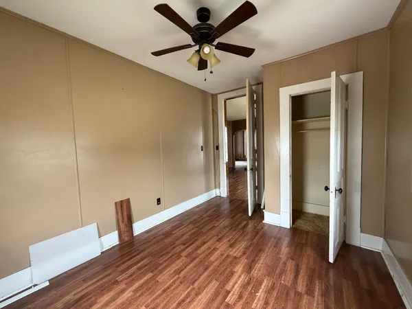a view of empty room with wooden floor and fan