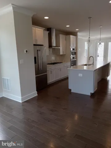 a large kitchen with stainless steel appliances a large counter top a stove a sink and a refrigerator