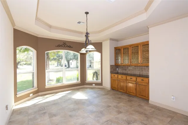 a view of an empty room with a window and kitchen view