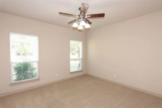 an empty room with windows and chandelier fan