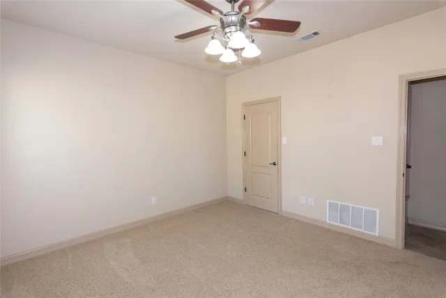 an empty room with a chandelier fan and windows