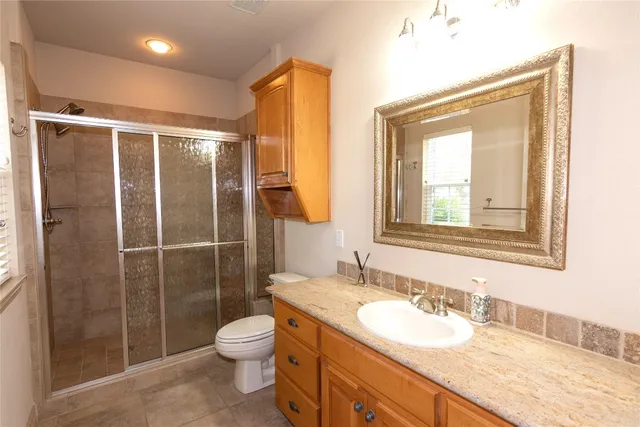 a bathroom with a granite countertop sink toilet a mirror and shower