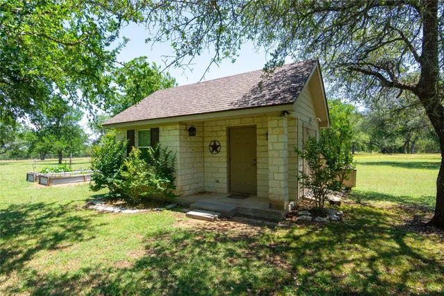 a view of a house with a small yard plants and large tree