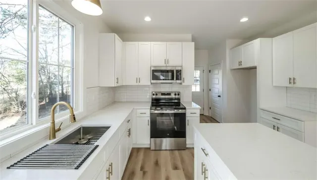 a kitchen with a sink a stove a refrigerator cabinets and a window