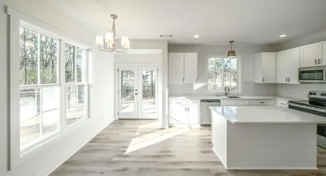 a kitchen with kitchen island granite countertop a stove top oven a sink and cabinets
