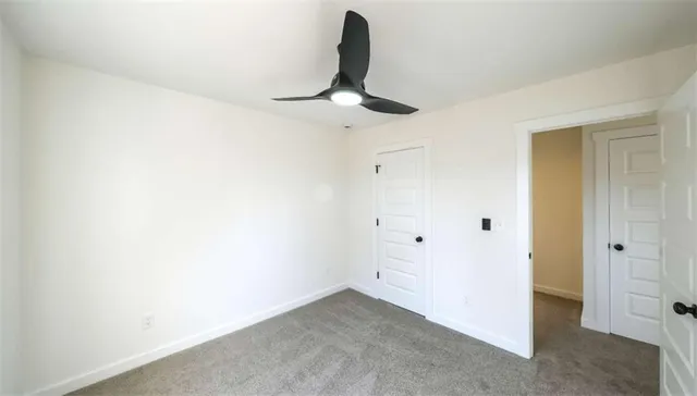 an empty room with a ceiling fan and carpet