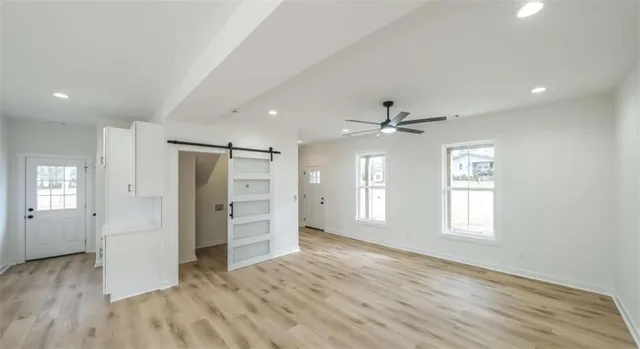 a view of an empty room with a window and wooden floor