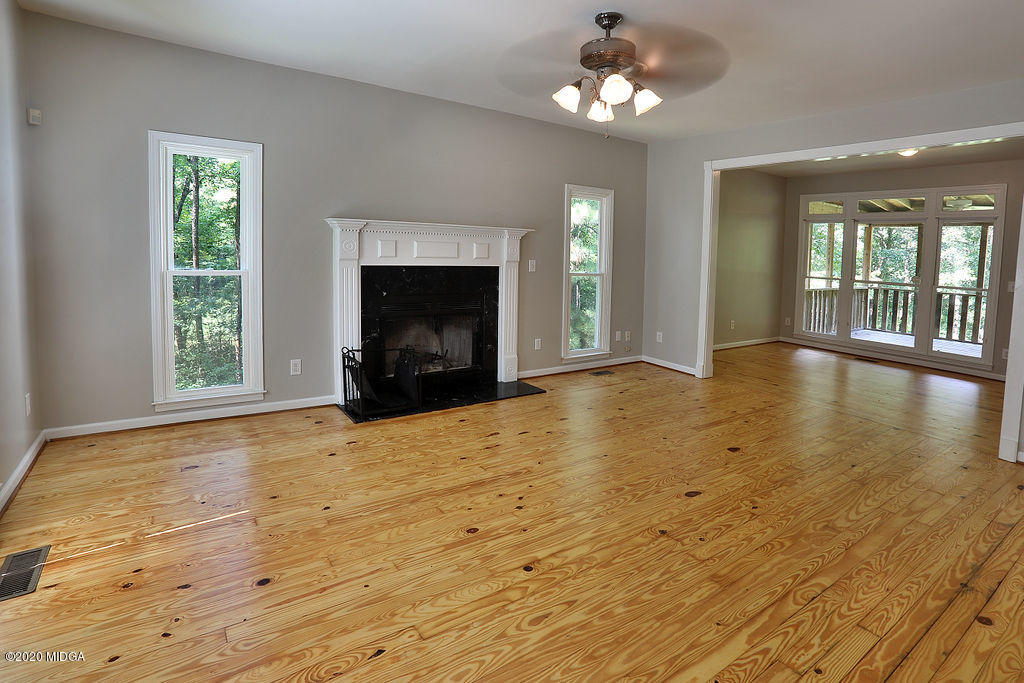 411 Lamar Road Macon, GA 31220 - Photo 3 of 22 an empty room with wooden floor fireplace and windows