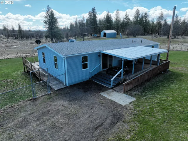 a view of a house with backyard and a forest
