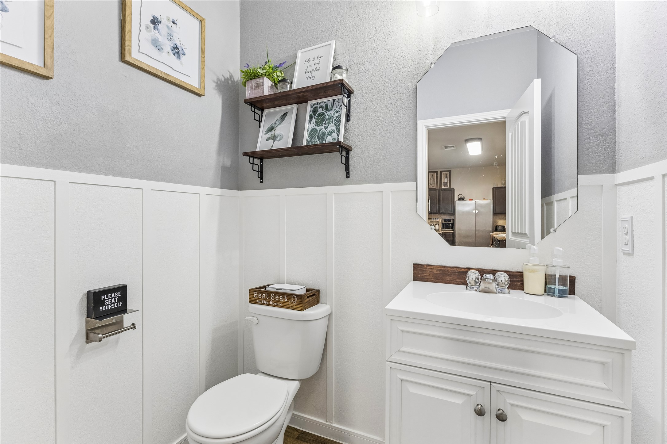 14409 Estuary Road Manor, TX 78653 - Photo 8 of 24 Bathroom featuring wainscoting, an octagonal wall mirror, and a corner vanity with a white basin