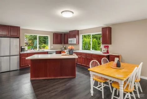 a kitchen with a table chairs a sink dishwasher window and dining table