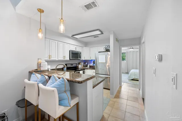 a kitchen with stainless steel appliances granite countertop a sink a stove a refrigerator cabinets and chairs