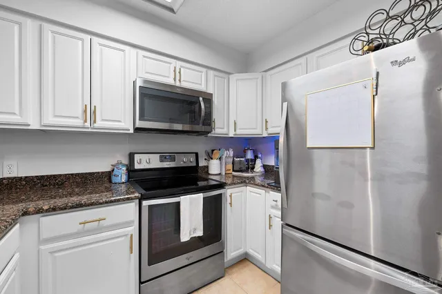 a kitchen with granite countertop white cabinets and refrigerator