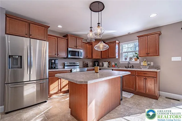 a kitchen with stainless steel appliances granite countertop a sink a stove a refrigerator cabinets and a window