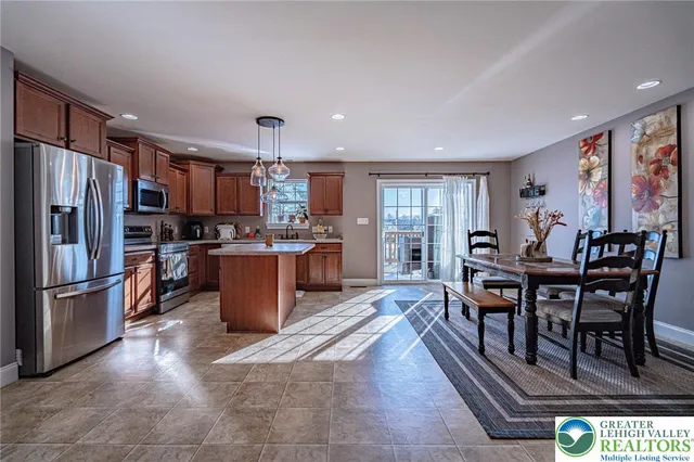 a kitchen with stainless steel appliances granite countertop a table chairs and a refrigerator