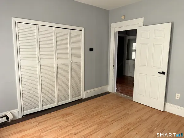 an empty room with wooden floor and closet area