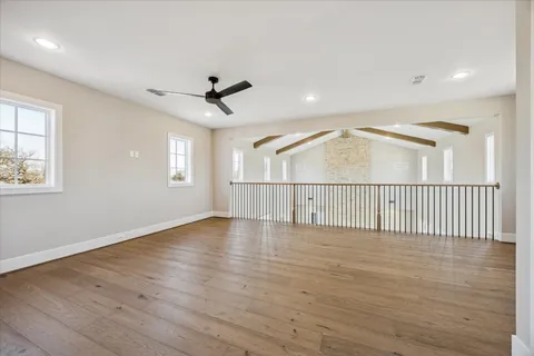 an empty room with wooden floor fan and windows