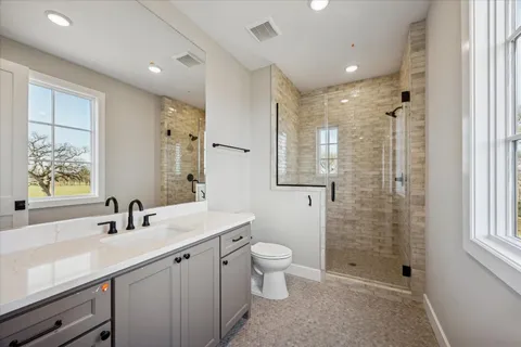 a bathroom with a double vanity sink toilet and shower