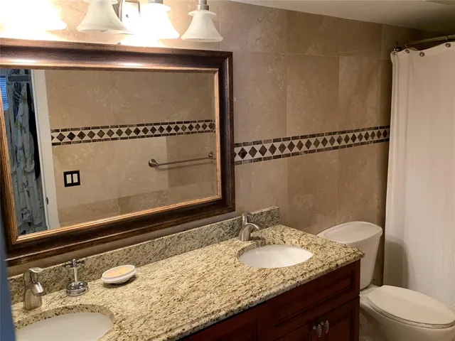 a bathroom with a granite countertop sink a mirror and a toilet